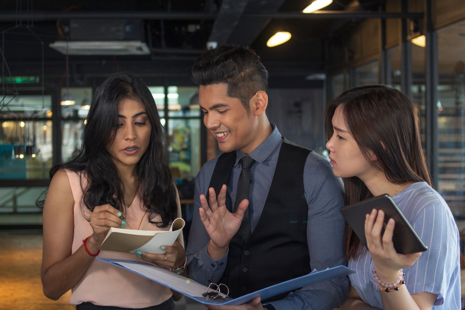 group of multi races Asian business person standing modrn indoor office, discussing business strategy hapily. company manager smiling and satisfy with the sales report presented by the coworkers