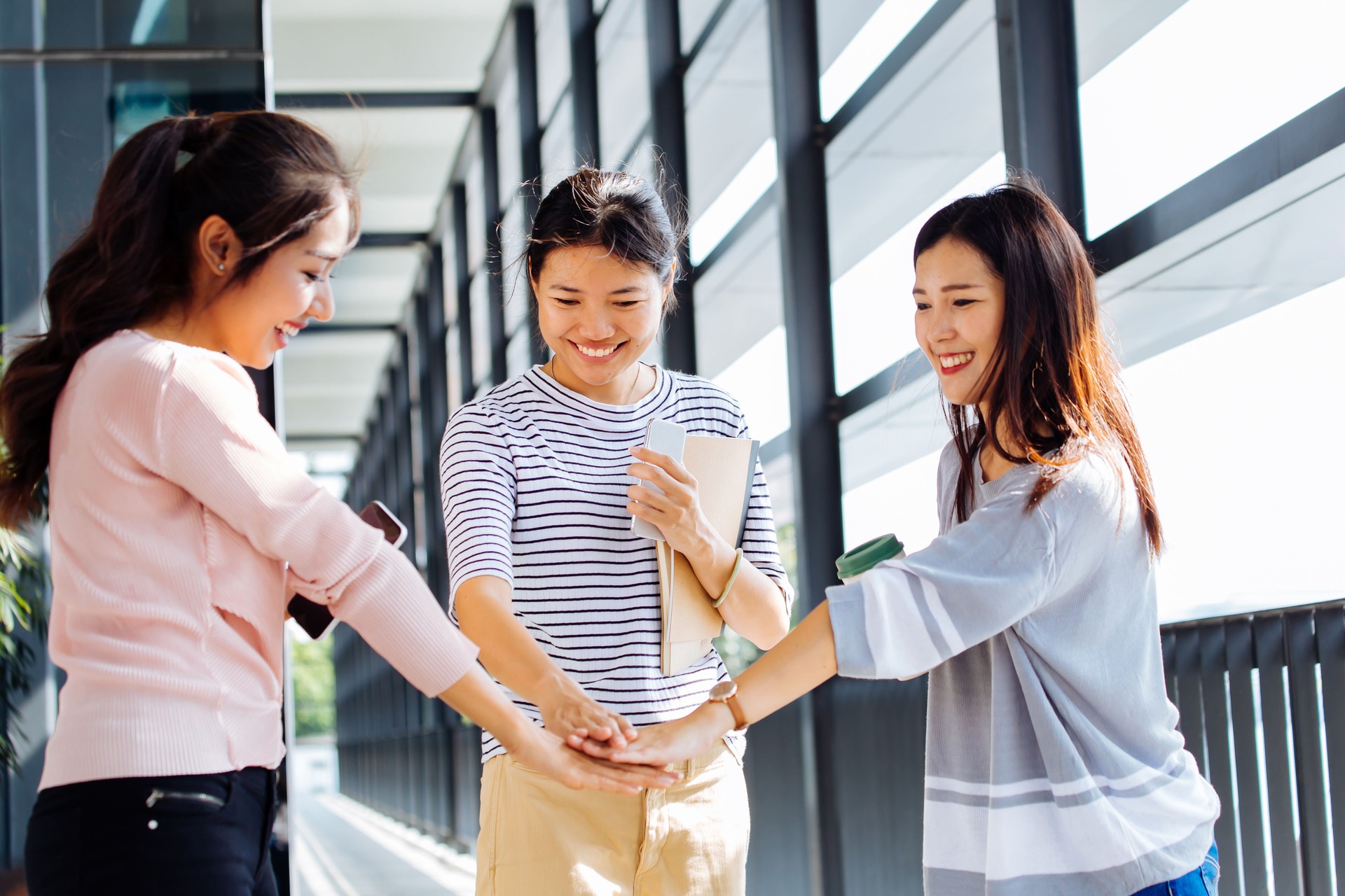 Asian students putting hands together in light corridor